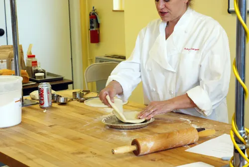 King Arthur Flour employee Robyn places rolled out pie crust into a pie pan. Taken at King Arthur Flour's Baking Education Center.