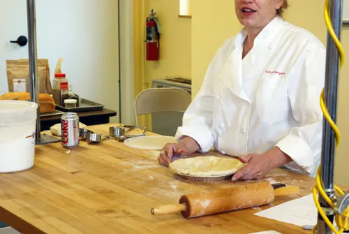 King Arthur Flour employee Robyn demonstrates tucking pie crust edges under in order to make prettier edges. Taken at the King Arthur Flour Baking Education Center.
