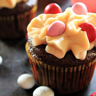 A chocolate cupcake with peanut butter frosting and pink, red, and white M&Ms. The batter is made with Shiner Bock beer.