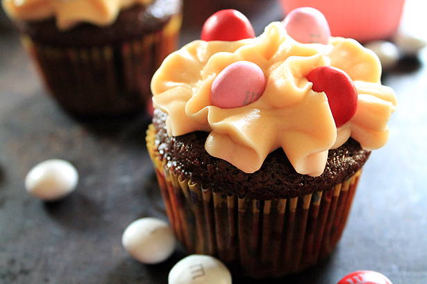 A chocolate cupcake with peanut butter frosting and pink, red, and white M&Ms. The batter is made with Shiner Bock beer. 