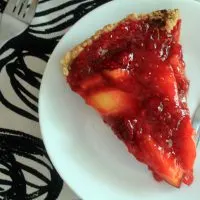 Peach Raspberry refrigerator pie on a white plate. Two forks sit nearby on a cloth napkin.