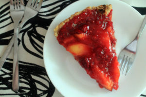 Peach Raspberry refrigerator pie on a white plate. Two forks sit nearby on a cloth napkin.